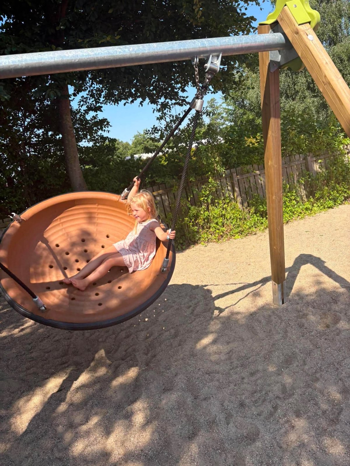 Pige gynger i redegynge en solrig sommerdag