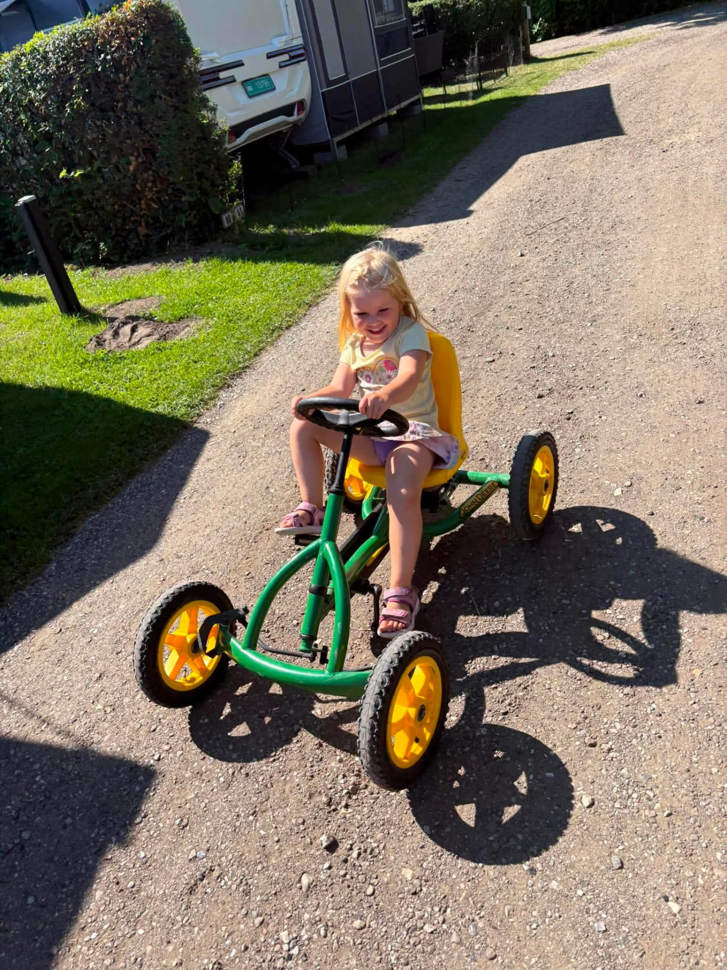 Pige kører gokart på campingpladsens grusvej