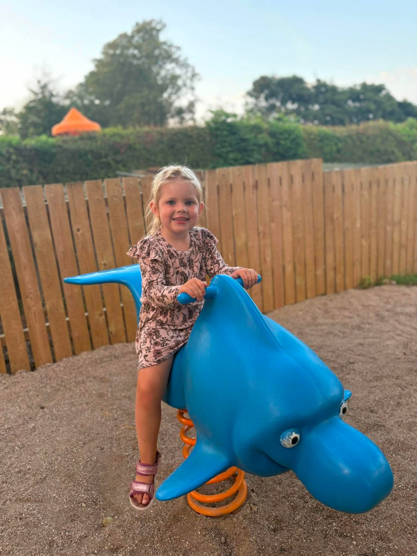 Pige leger på blå fjedergynge ved legepladsen